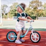 Balans bicikl Alex za decu tirkizno plave boje sa podesivim kormanom i podesivim sedištem, prikazan kako ga vozi devojčica