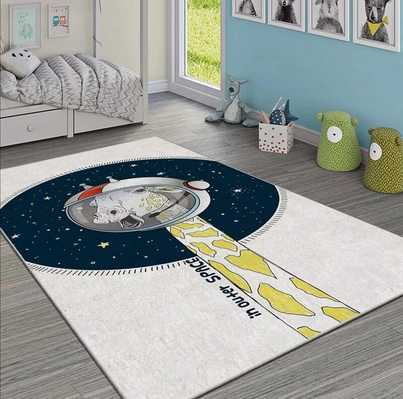 tepih-za-decu-zirafa-kosmonaut-slika-1 Tepih za decu Žirafa kosmonaut, od pliša i sa kožnom osnovom, prikazan na podu dečije sobe