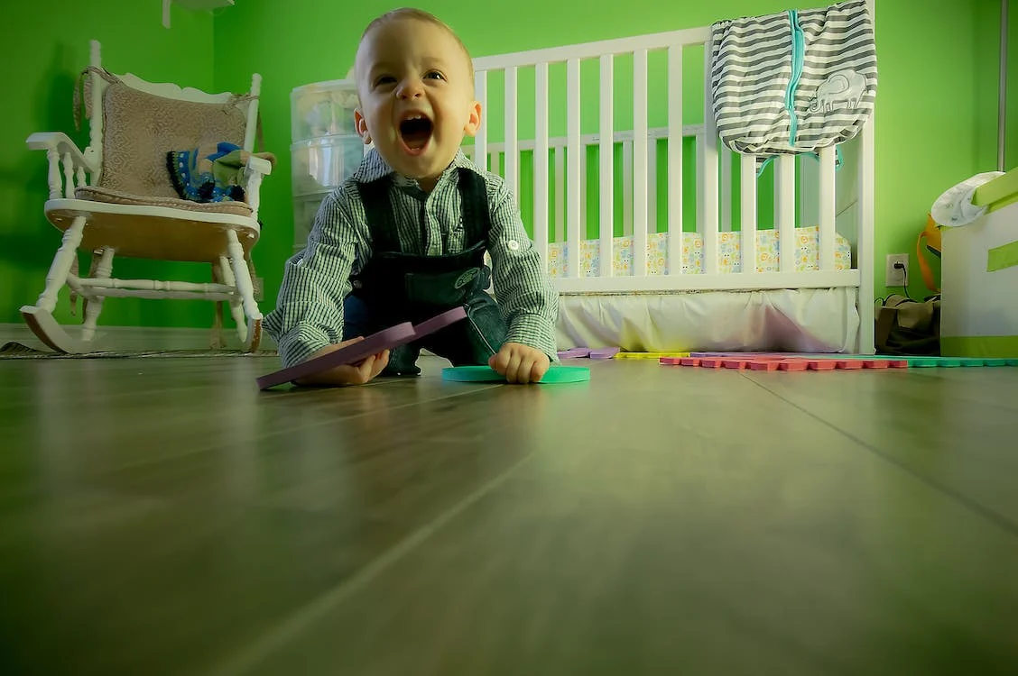 beba puza na podu sobe sa igračkama oko sebe
